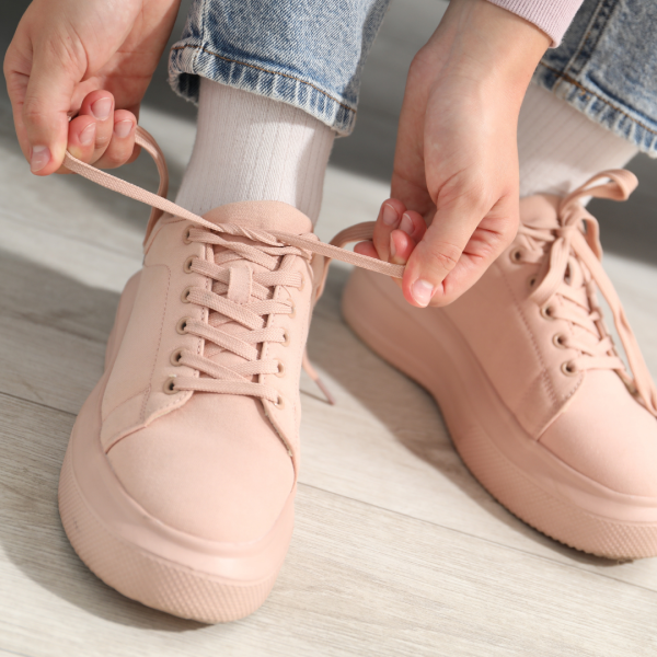 Mujer se aparra zapatillas de color rosa pastel.